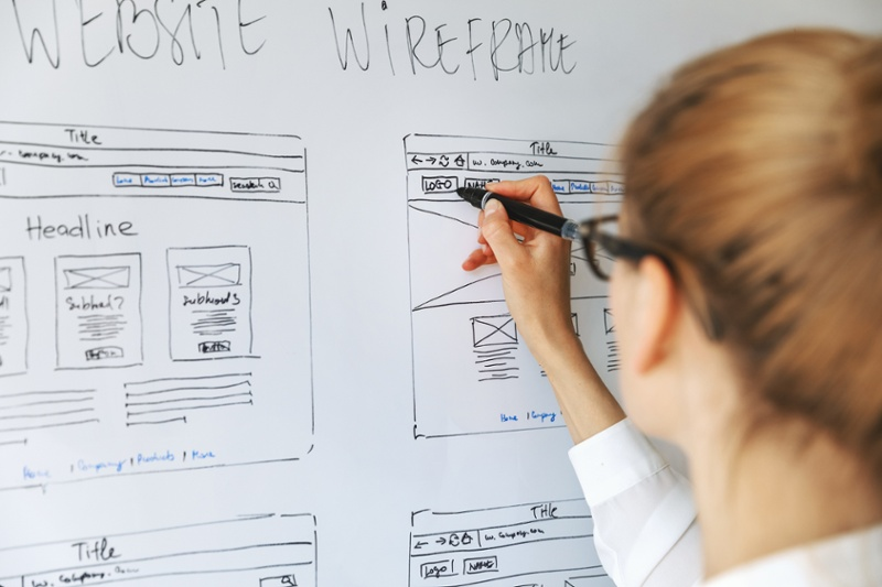 Woman writing on a whiteboard about website wireframes.